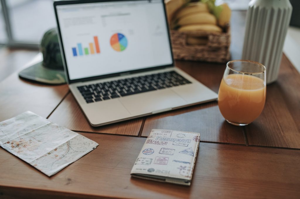 laptop computer stands on the table in the kitchen with a glass of juice and fruit